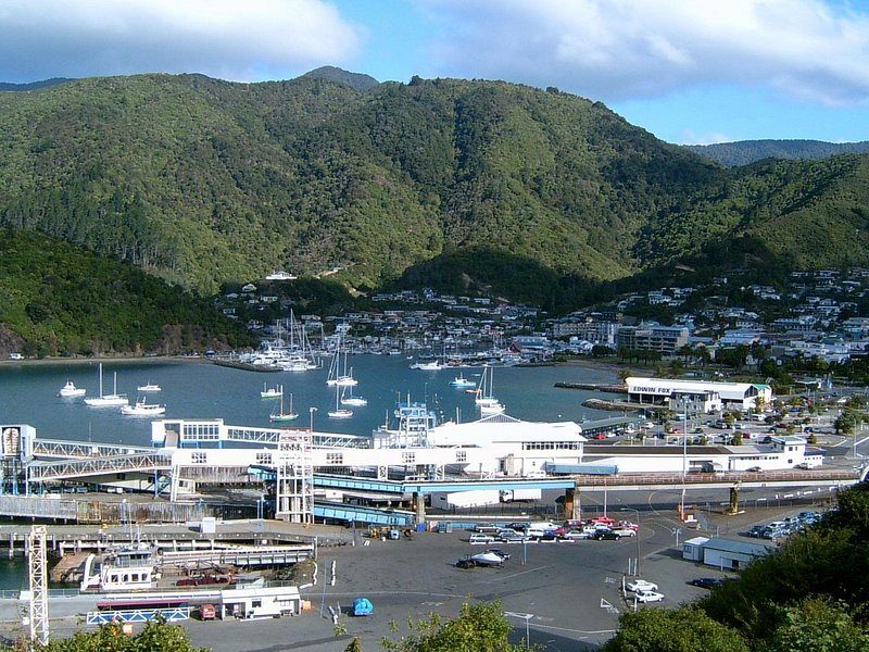 A harbour town's marina and ferry berths below forested hills