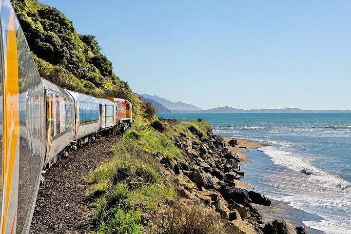 A passenger train on a coastal line between the cliffs and the sea